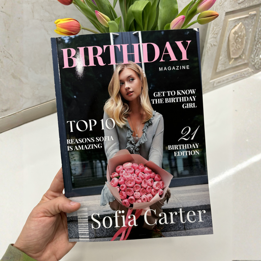 A hand holds a copy of Sofia Carter's 'Birthday Magazine' featuring a cover with pink roses and text about Sofia Carter. Tulips are visible at the top of the frame against a tiled wall background.