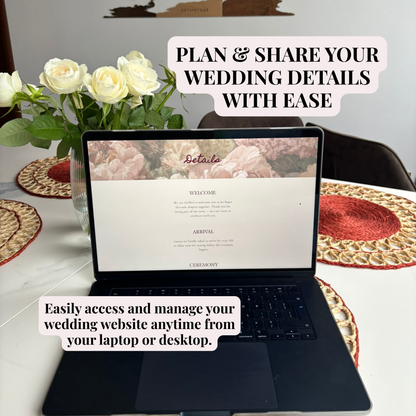 An open black laptop sits on a white table, displaying a wedding website template. White roses in a vase and woven placemats are visible around it.
